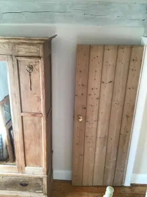 a room with a wooden cabinet next to a wall at Inglenook Cottage in Grange Over Sands