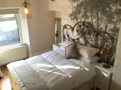 a bedroom with a large white bed in front of a wall at Inglenook Cottage in Grange Over Sands