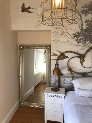 a bedroom with a mirror and a bed and a lamp at Inglenook Cottage in Grange Over Sands