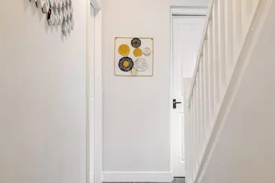 a hallway with white walls and a white stair case at The Central Suite Blackpool-Best Holiday Letting Home in Blackpool in Blackpool