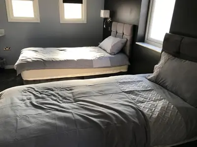 a bedroom with two beds and two windows at Cozy Rooms in Liverpool
