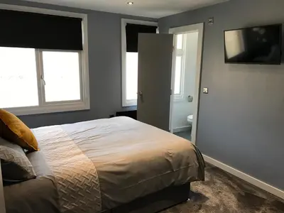 a bedroom with a bed and two windows and a television at Cozy Rooms in Liverpool