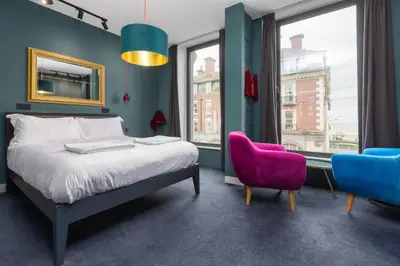 a bedroom with a bed and a pink chair at ART B&B in Blackpool