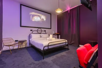 a bedroom with purple walls and a bed and chairs at ART B&B in Blackpool