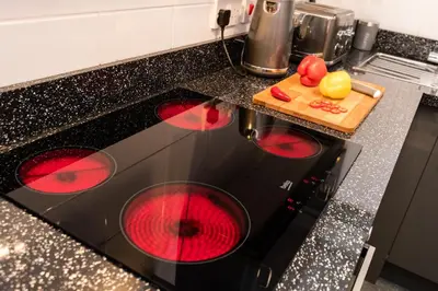 a black stove top oven with red burners in a kitchen at 1 Bedroom Newton Apartment l Free Parking l Wigan Royal Infirmary l Haigh Hall l Central Location in Wigan