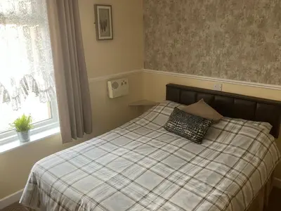 a bedroom with a bed with a plaid blanket and a window at Pearl Hotel in Blackpool