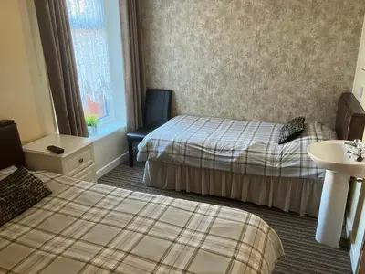 a hotel room with two beds and a sink at Pearl Hotel in Blackpool