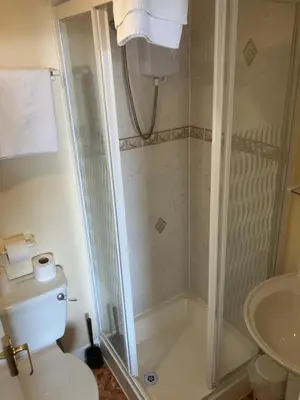 a bathroom with a shower with a toilet and a sink at Pearl Hotel in Blackpool