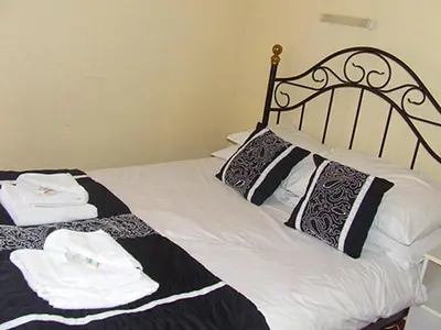 a bed with black and white sheets and towels on it at The Woodfield Hotel , Indoor Heated swimming pool, Spacious lounge and Bar in Blackpool