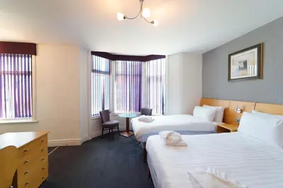 a hotel room with two beds and a desk at The Royal Alexandra Hotel by Compass Hospitality in Blackpool