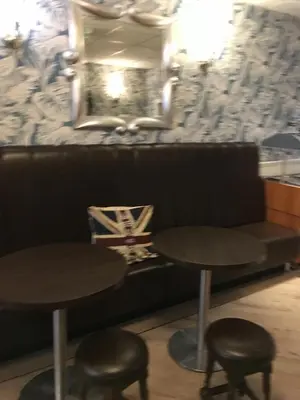 two tables and stools in a restaurant with a wall at The Aspire in Blackpool
