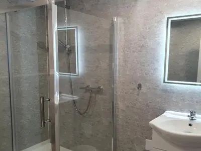 a shower with a glass door next to a sink at South Beach Kings Promenade Hotel in Blackpool
