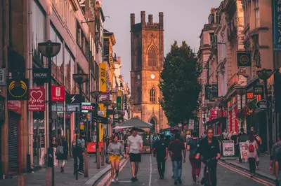 a group of people walking down a street with a clock tower at EPIC Apart Hotel - Seel Street in Liverpool