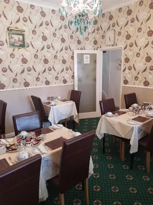 a dining room with tables and chairs and a wall at Thornhill Blackpool in Blackpool