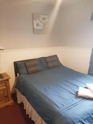 a bedroom with a bed with blue sheets and a table at Thornhill Blackpool in Blackpool