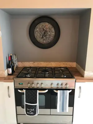 a kitchen with a stove with a clock on the wall at Cosy house set in historic town of Clitheroe in Clitheroe