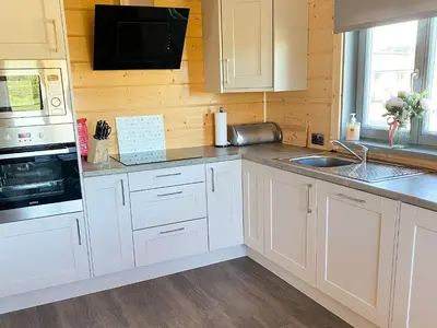 a kitchen with white cabinets and a sink at Cedar Lodge - Uk30008 in Lindal in Furness