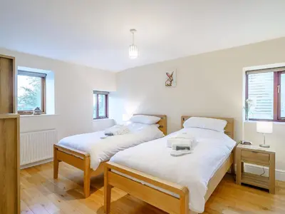 two beds in a room with white walls and wooden floors at Adamsons Barn in Inglewhite