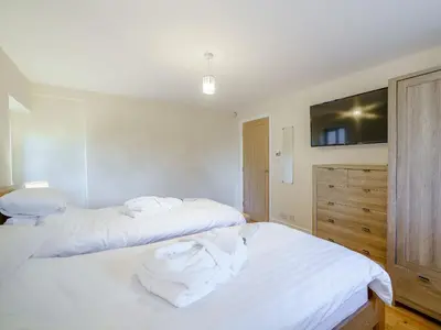 two white beds in a room with a tv on the wall at Adamsons Barn in Inglewhite