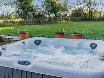 a hot tub in a yard with potted plants at Adamsons Barn in Inglewhite