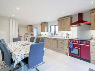 a kitchen with a table and a red stove at Adamsons Barn in Inglewhite