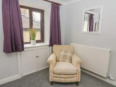 a living room with a chair and a window at Rose Cottage in Grange Over Sands