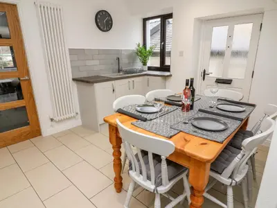 a kitchen and dining room with a wooden table and chairs at Rose Cottage in Grange Over Sands