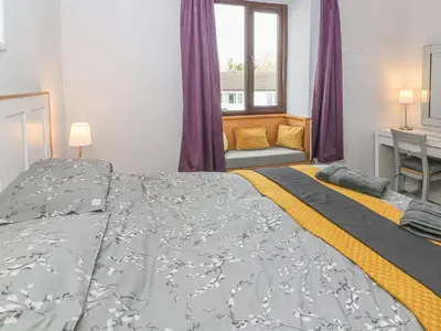 a bedroom with a large bed and a window at Rose Cottage in Grange Over Sands
