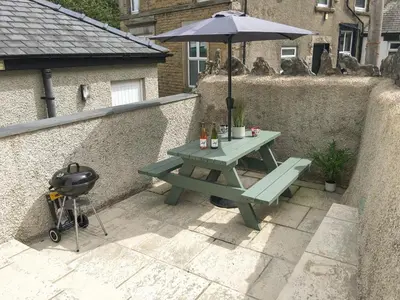 a picnic table with an umbrella and a grill at Rose Cottage in Grange Over Sands