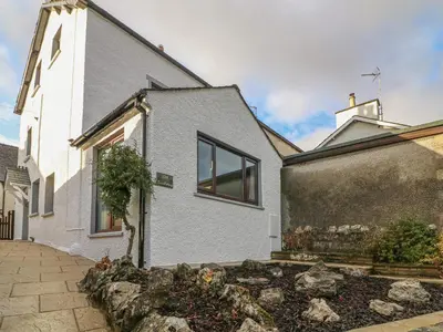 a white house with a stone wall at Rose Cottage in Grange Over Sands