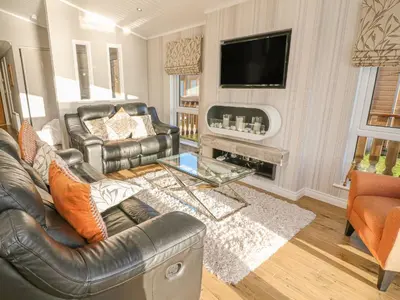 a living room with leather furniture and a flat screen tv at Shore Beats Work - Capenwray 10 in Carnforth