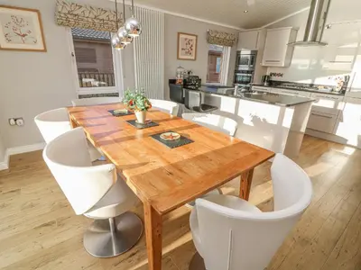 a kitchen and dining room with a wooden table and chairs at Shore Beats Work - Capenwray 10 in Carnforth