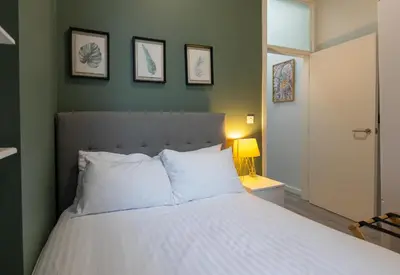 a bedroom with a white bed with three pictures on the wall at City Haven Preston in Preston