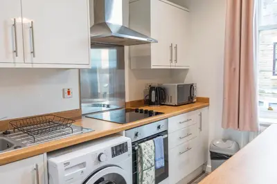 a kitchen with white cabinets and a washer and dryer at City Haven Preston in Preston