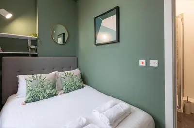 a bedroom with a bed with white sheets and a mirror at City Haven Preston in Preston
