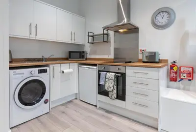 a kitchen with a washing machine and a clock on the wall at City Haven Preston in Preston