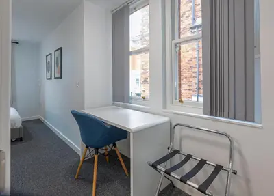 a room with a white desk and a blue chair at City Haven Preston in Preston