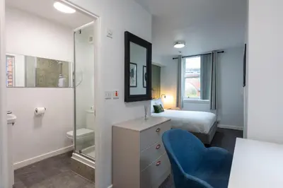 a bedroom with a bed and a blue chair at City Haven Preston in Preston