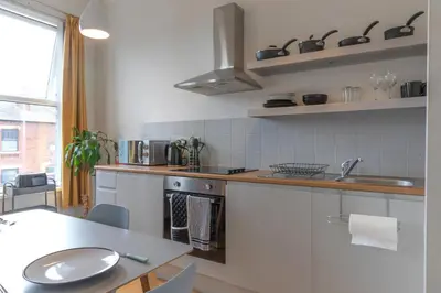 a kitchen with white cabinets and a sink and a table at Fulwood Heights in Preston