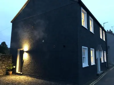 a black building with a light on the side of it at The Old Hay Shed in Cartmel