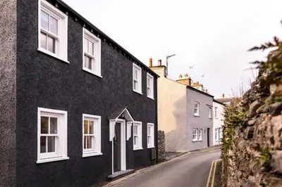 a black house with white windows on a street at The Old Hay Shed in Cartmel