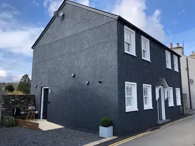 a black house with white windows on a street at The Old Hay Shed in Cartmel