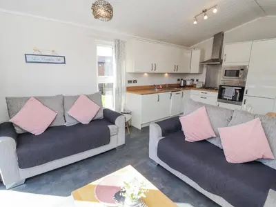 a living room with two couches and a kitchen at Duckling Lodge in Carnforth