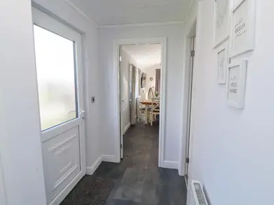 a hallway with a white door and a window at Duckling Lodge in Carnforth