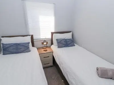 two twin beds in a bedroom with a night stand at Duckling Lodge in Carnforth