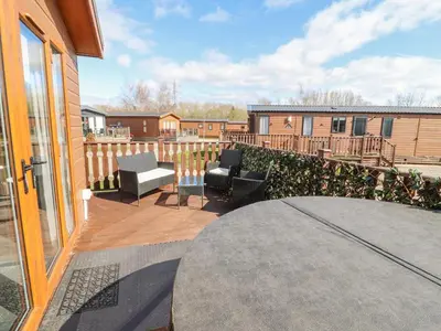 a patio with chairs and a table on a balcony at Duckling Lodge in Carnforth
