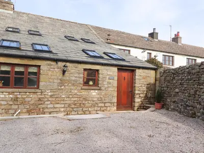 a stone house with a red door and a stone wall at Usherwoods Barn in Lancaster