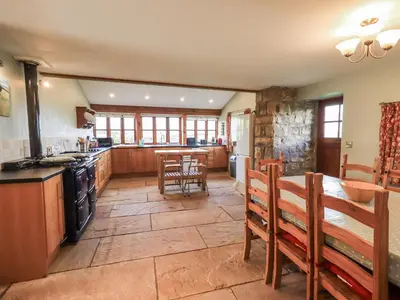 a large kitchen with wooden cabinets and a table and chairs at Usherwoods Dairy in Lancaster