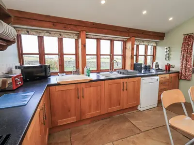 a large kitchen with wooden cabinets and windows at Usherwoods Dairy in Lancaster