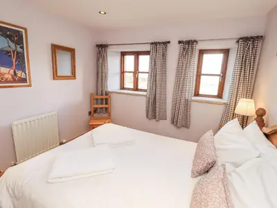 a bedroom with a white bed and two windows at Usherwoods Dairy in Lancaster